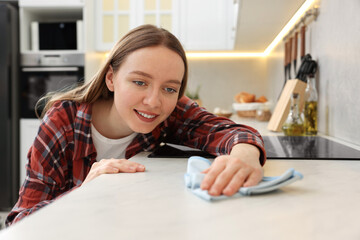 Canvas Print - Woman with microfiber cloth cleaning white marble countertop in kitchen