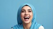 © sevenSkies - young middle eastern woman on plain bright blue background laughing hysterically looking at camera background banner template ad marketing concept from Generative AI