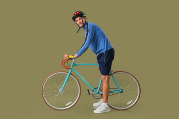 Wall Mural - Young man riding bicycle on khaki background