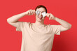 © Pixel-Shot - Funny young man with condoms on red background. Safe sex concept