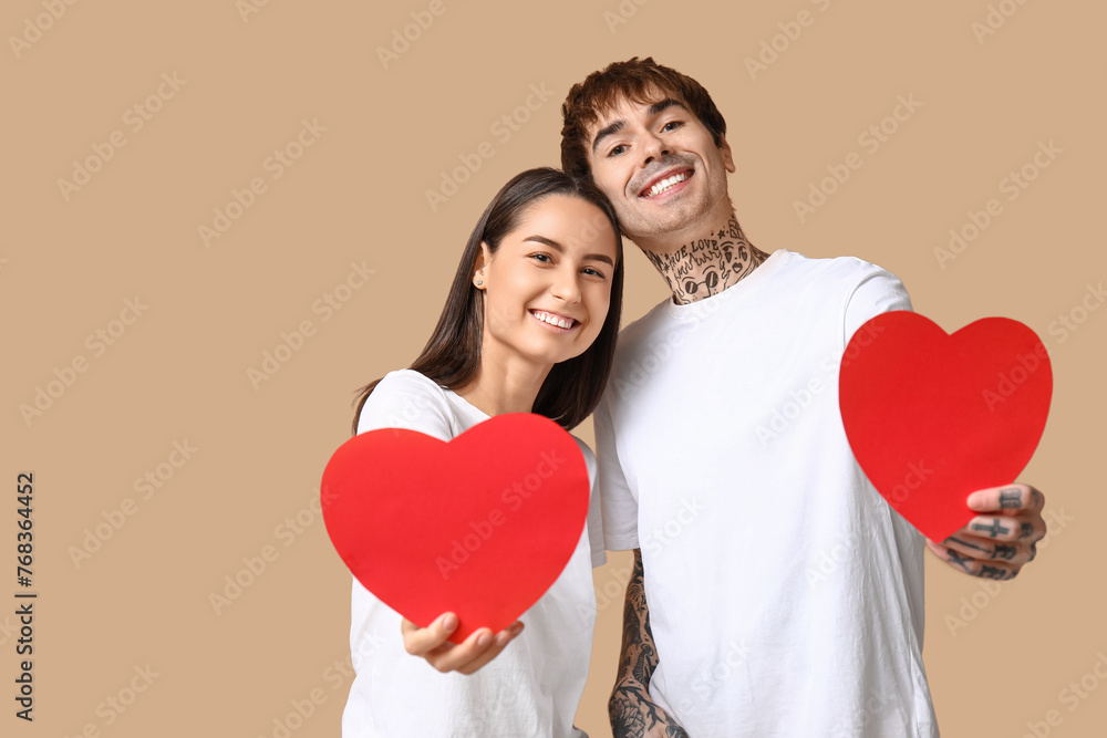 Young couple with paper hearts on beige background