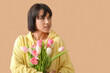 © Pixel-Shot - Beautiful young woman with bouquet of tulips on beige background. International Women's Day