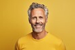 Handsome middle-aged man in a yellow t-shirt on a yellow background