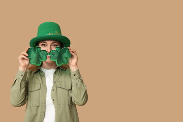 Mature woman in hat with eyeglasses on beige background. St. Patrick's Day celebration