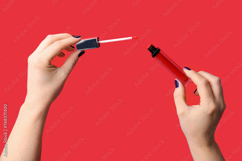 Female hands with liquid lipstick on red background