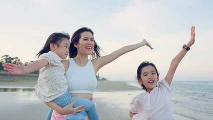 Wall Mural - Asian mother and daughters walking on the beach during summer together.  