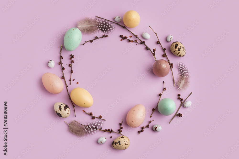 Wreath made of branches, Easter eggs and feathers on purple background