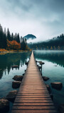 Fototapeta Sport - wooden bridge path leads to a serene lake, calm water, natural pine tree forest, and misty mountains created with Generative AI Technology