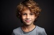 Portrait of a cute little boy with curly hair over dark background
