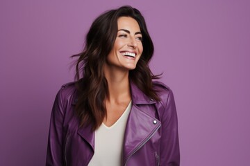 Wall Mural - Portrait of a happy young woman in purple leather jacket over violet background