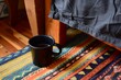 black coffee cup with a colorful bedside rug underneath