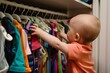baby reaching for colorful clothes in an organized closet