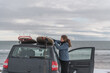 © Cavan Images - Woman removing surf board from roof of car