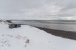 © Cavan Images - Small car parked in front of ocean during winter surf day