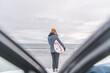 © Cavan Images - Woman standing in front of the ocean with surf board winter iceland