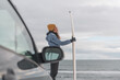 © Cavan Images - Woman standing next to surf board winter iceland