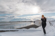 © Cavan Images - Woman walking on beach with surf board winter iceland