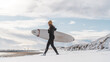 © Cavan Images - Woman walking on beach with surf board winter iceland