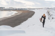 © Cavan Images - Woman walking on beach with surf board winter iceland