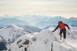 © Cavan Images - Mountaineer steadies himself with his hand on mountain ridge