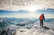 © Cavan Images - Rear view of mountaineer standing on snow covered summit