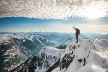 Mountaineer Raises His Ice Axe On The Summit Of A Mountain
