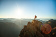 © Cavan Images - successful hiker wearing backpack stands on mountain summit, sunset