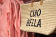 Braided bag with leather handle printed with Italian text Ciao Bella in a boutique. Ciao Bella means Hi Beautiful in the English language.