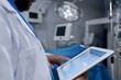 surgeon consulting digital tablet with patients records in or
