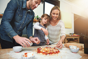 Learning, smile and family baking pizza in kitchen together, bonding and happy in home. Food, mother and father with kid cooking, teaching and help parents prepare for lunch with cheese at table