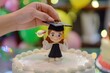 hand placing mortarboard figurine on the cake