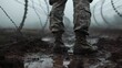 Closeup of the boots and pants of an soldier standing in mud 