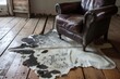 cowhide rug on wooden floor, leather armchair