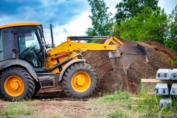 Wall Mural - A bulldozer or a loader is actively digging into a large pile of dirt, moving the earth to clear or level the area