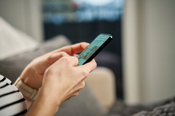 Close-up person casually using smartphone with social media feed displayed on screen, suggesting engagement with digital content. Woman using mobile phone at home