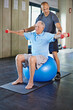 © peopleimages.com - Physiotherapist, helping and senior man with weights, training and elderly support for care. Men, gym and exercise for health, wellness and coaching with yoga ball for mature rehab and wellbeing