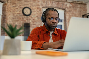 Wall Mural - African american young man typing on laptop and looking serious