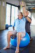 © peopleimages.com - Physiotherapist, helping and senior man with elastic, training and elderly support for care. Men, gym and exercise for health, wellness and coaching with yoga ball for mature rehab and wellbeing