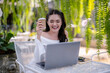 © Wasana - Young woman enjoying a video call using a laptop at an outdoor cafe. Enjoy chatting on laptop screen.