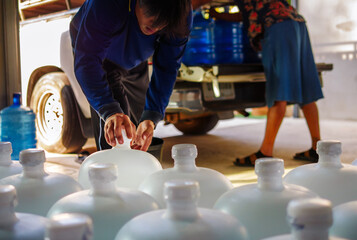 Workers lift drinking water .clear and clean in white plastic gallon into the back of a transport truck purified drinking water inside the production line to prepare for sale. Water drink factory