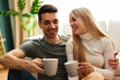 Beautiful young happy couple enjoying coffee at home on sofa