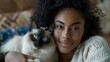 Beautiful young black woman hugging her siamese cat
