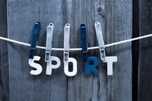 Close-up Of Three Colorful Clothespins Holding The Word "sport" On A Clothesline.