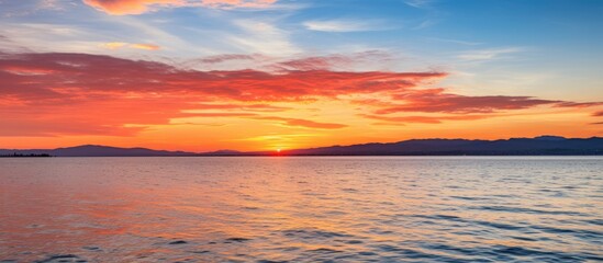 Wall Mural - A serene view of a colorful sunset over the ocean, with a small boat gently floating in the water, creating a tranquil and picturesque scene