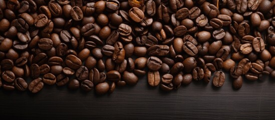 Scattered roasted brown coffee beans arranged on a black background creating a textured and rich coffee bean display