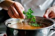 chef garnishing soup with a sprig of fresh parsley