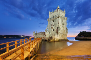 Wall Mural - Belem Tower or Tower of St Vincent - famous tourist landmark of Lisboa and tourism attraction - on the bank of the Tagus River (Tejo) after sunset in dusk twilight with dramatic sky. Lisbon, Portugal