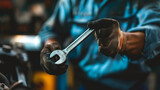 Fototapeta  - An auto mechanic at a car service center, holding a wrench, with a blurred background
