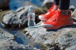 bright sneakers standing on rock, clear water bottle nearby