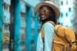 Happy young african american tourist woman wearing beach hat, sunglasses and backpacks going to travel on holidays on citiy background